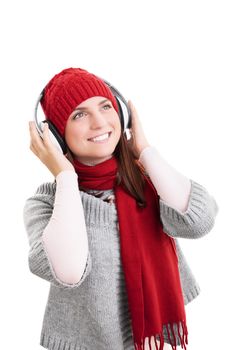 Beautiful smiling girl with red scarf and hat in winter clothes, listening to music on her headphones, isolated on white background.