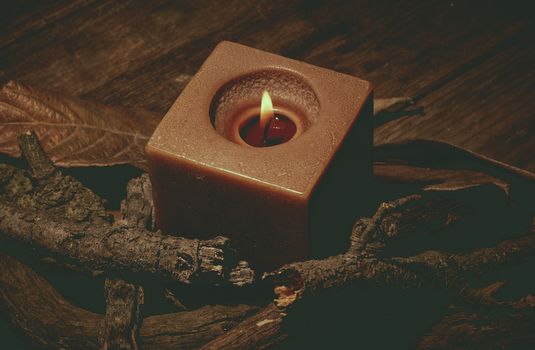 candle in darkness with pieces of wood in brown