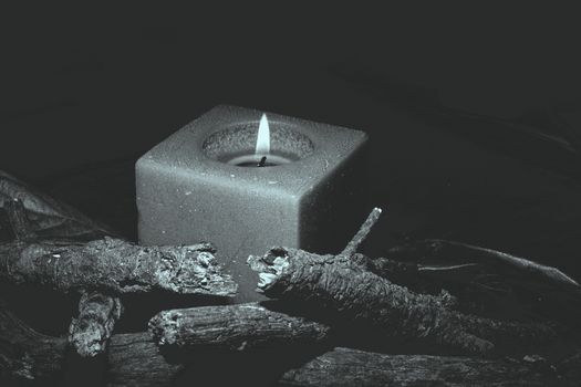 candle in darkness with pieces of wood in brown