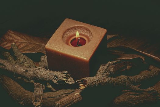 candle in darkness with pieces of wood in brown