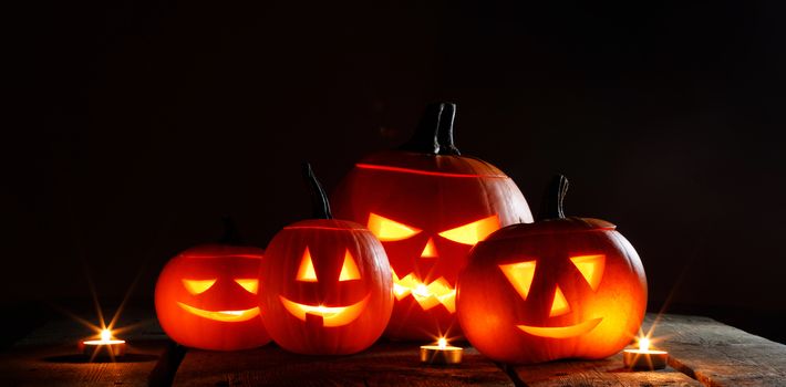 Halloween pumpkin head jack o lantern and candles on black background