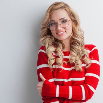 Portrait of a beautiful girl wearing glasses and red striped sweater on white background
