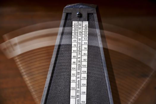 Close up of a vintage metronome with swinging pendulum