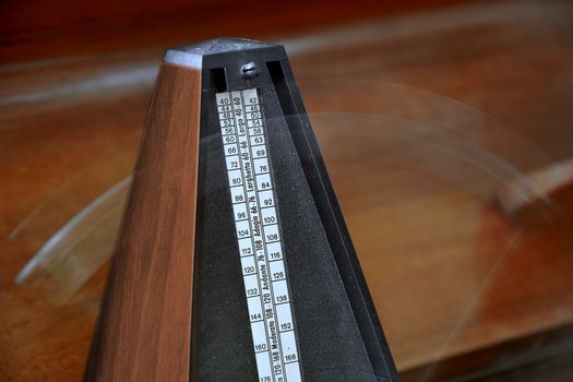 Close up of a vintage metronome with swinging pendulum