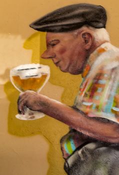 Caricature of a paunchy figure holding a glass of orval in his hand on a wall of a cafe in Gerouville