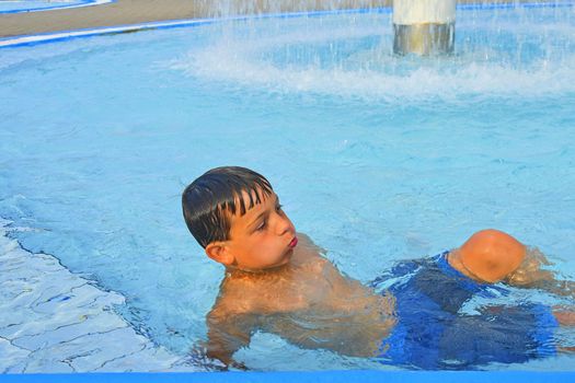 Summertime and swimming activities for happy children in the pool. Cute boy in water park. Summer and happy chilhood concept. 