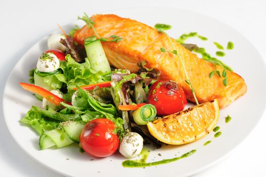 Grilled salmon and fresh vegetable salad at the plate