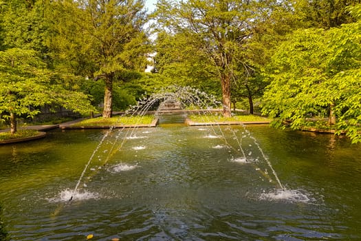 Castle park in summer with fountain in the bright day. Water Environment concept