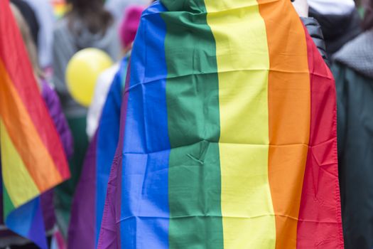 Person Carrying Rainbow Flag over Sholders in Pride Parade.
