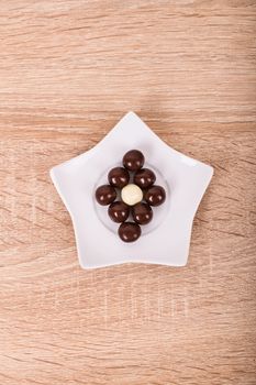 Chocolate balls on a star shaped ceramic white saucer, on a wooden background.