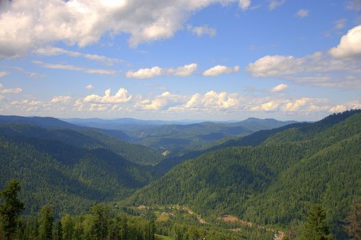 A fertile valley that stretches at the foot of high mountains. Altai, Siberia, Russia.