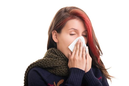 Cold and flu season. Portrait of a girl in winter clothes blowing her nose, isolated on white background.
