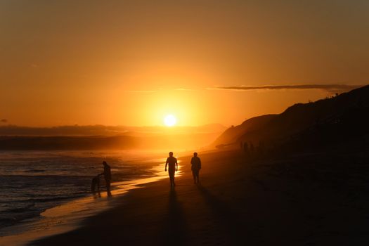 People turn to shadows and silhouettes as the beach darkens moments before the sunset, Mossel Bay, South Africa