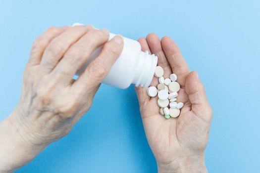 Medicine pills or capsules in elder hand.