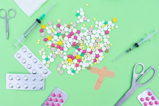 Подпись:Assorted pharmaceutical medicine pills, tablets and capsules over green background