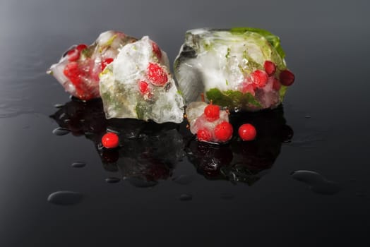 Fresh fruits and vegetable frozen in ice cubes on black background. Fresh healthy summer eating.