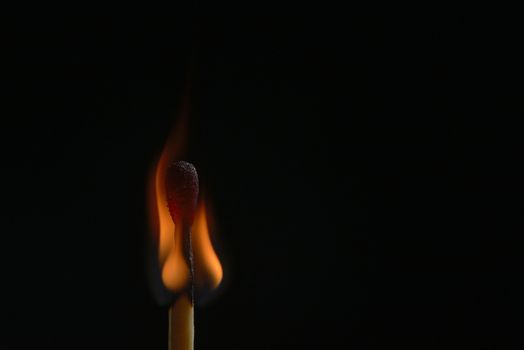 Head of burning match on black background