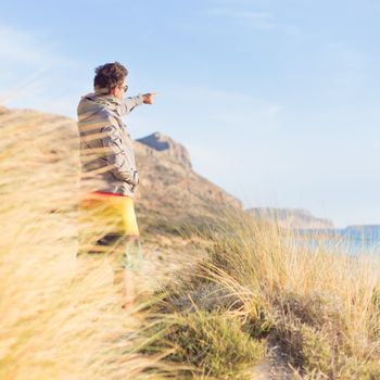 Sporty active man pointing hand on horizon, enjoying beauty of nature, freedom and life at beautiful landscape. Active lifestyle outdoors.