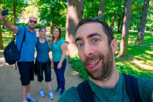 Group of young men and woman taking a selfie picture with a smartphone or camera at the park.