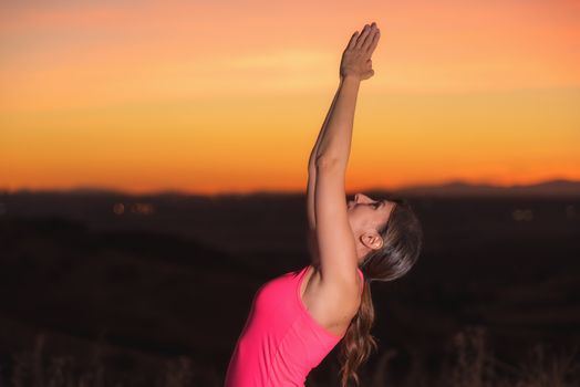 Young beautiful woman practicing Yoga at sunset