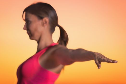 Young beautiful woman practicing Yoga at sunset