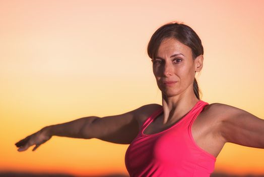 Young beautiful woman practicing Yoga at sunset