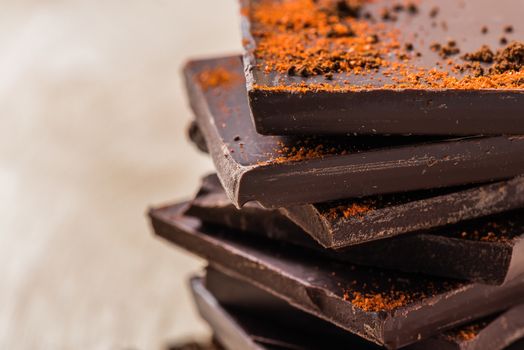 Stack of Chocolate Bars with Cayenne powder on light background