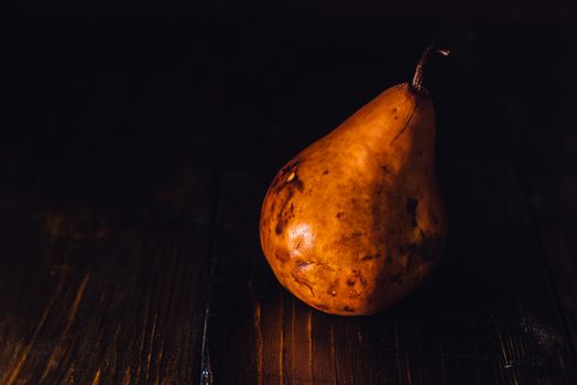 One Golden Pear on Dark Wooden Background.