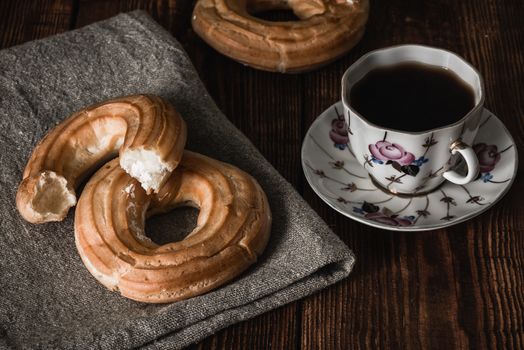 Round eclairs with cup of coffee. Sweet breakfast.