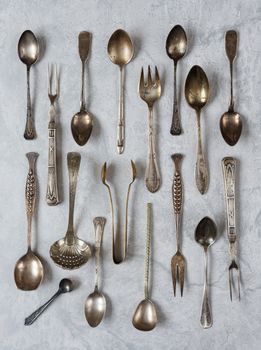 Various vintage silverware on a background of gray concrete surface