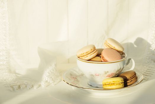 Beautiful elegant porcelain cup filled with almond cookies, on the background of white lace fabric