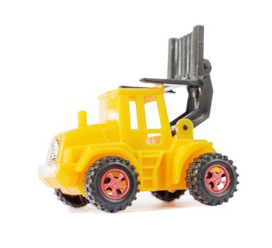 Yellow toy forklift made of plastic, with a raised loader, isolated on a white background, side view