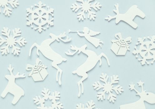 Christmas background composed of white christmas decoration: snowflakes, deers, flying angel and gift boxes on blue background. Christmas wallpaper. Flat lay composition for websites, social media, business owners, magazines,  bloggers, artists etc.