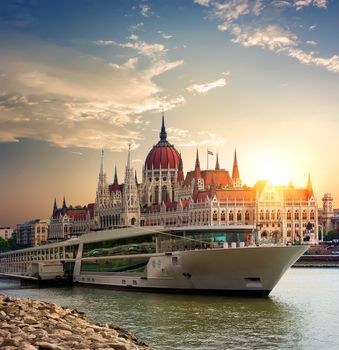 Sunset over Hungarian Parliament and touristic boat on Danube river