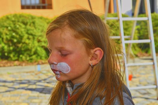 Beautiful young girl with face painted like a rabbit.  Face painting on child face.