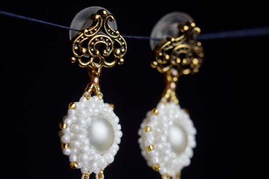 handmade jewelry made of beads in macro. earrings from white beads. earrings from stones. beautiful ornaments. earrings from white beads. ornaments on a black background