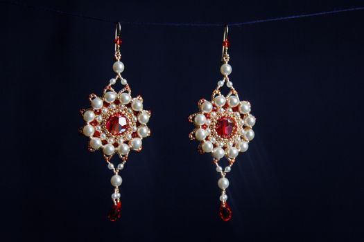 handmade jewelry made of beads in macro. earrings from white beads. earrings from stones. beautiful ornaments. earrings from red beads. ornaments on a black background