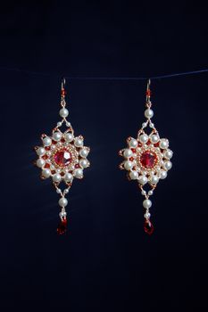 handmade jewelry made of beads in macro. earrings from white beads. earrings from stones. beautiful ornaments. earrings from red beads. ornaments on a black background