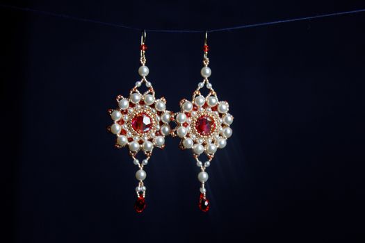 handmade jewelry made of beads in macro. earrings from white beads. earrings from stones. beautiful ornaments. earrings from red beads. ornaments on a black background