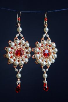 handmade jewelry made of beads in macro. earrings from white beads. earrings from stones. beautiful ornaments. earrings from red beads. ornaments on a black background