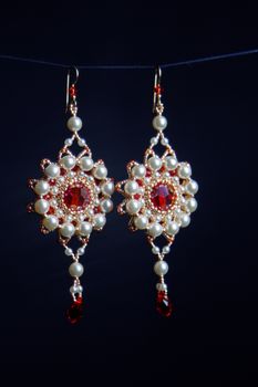 handmade jewelry made of beads in macro. earrings from white beads. earrings from stones. beautiful ornaments. earrings from red beads. ornaments on a black background