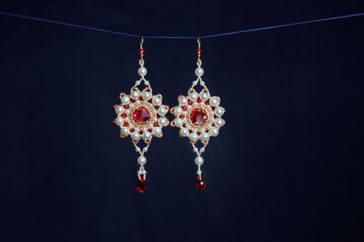 handmade jewelry made of beads in macro. earrings from white beads. earrings from stones. beautiful ornaments. earrings from red beads. ornaments on a black background