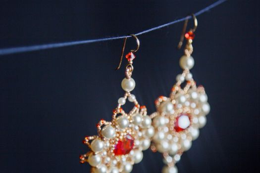 handmade jewelry made of beads in macro. earrings from white beads. earrings from stones. beautiful ornaments. earrings from red beads. ornaments on a black background