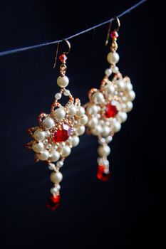 handmade jewelry made of beads in macro. earrings from white beads. earrings from stones. beautiful ornaments. earrings from red beads. ornaments on a black background