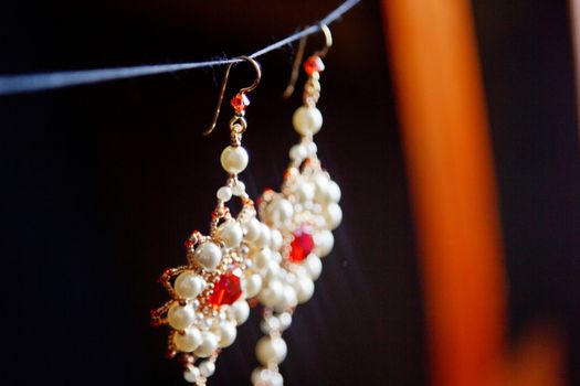 handmade jewelry made of beads in macro. earrings from white beads. earrings from stones. beautiful ornaments. earrings from red beads. ornaments on a black background