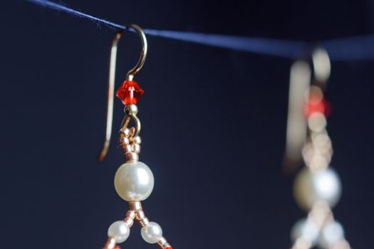 handmade jewelry made of beads in macro. earrings from white beads. earrings from stones. beautiful ornaments. earrings from red beads. ornaments on a black background