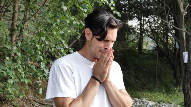 Young handsome man standing in nature, sad, worried or upset, crying