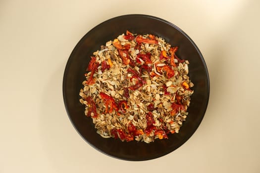 A tasty salt granola with pepper in black bowl on baige bakground. Concept of nutrient and healty breakfast or meal and vegan or vegetarian food.