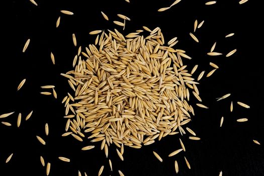 Pile of oat seeds isolated on black background. Top view