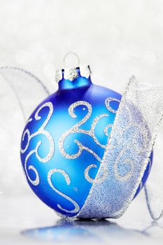 Beautiful blue christmas ball and ribbon on abstract glitter background close-up